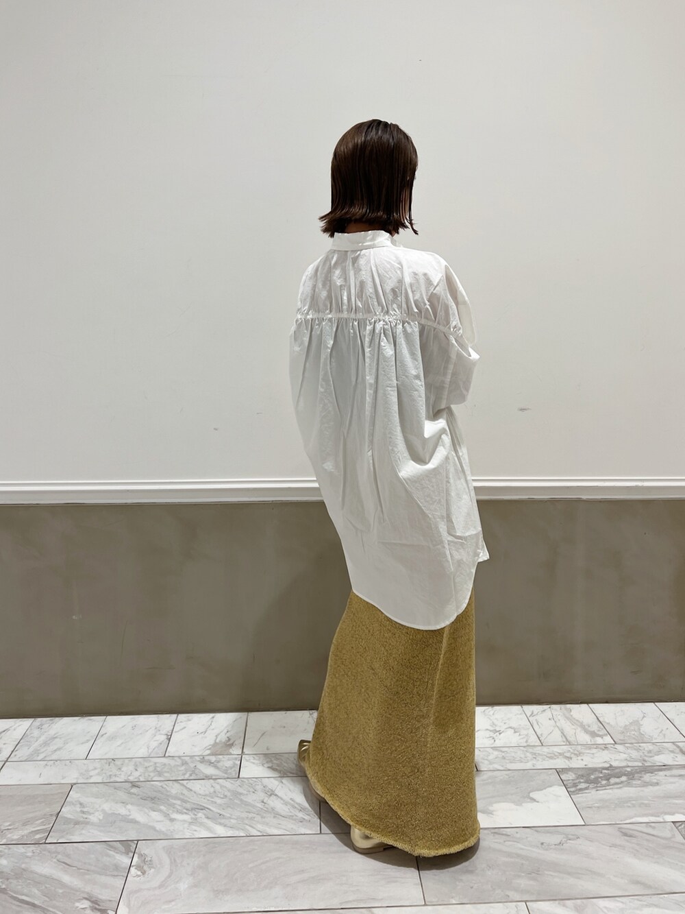 ホワイト系のシャツ/ブラウス、イエロー系のパンプス、ベージュ系のスカートを着用したレディースの冬コーディネートの4枚目の写真