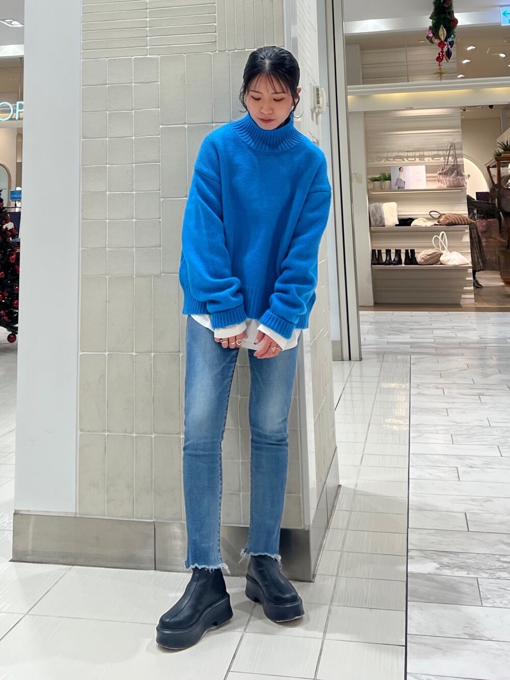 ブルー系のニット/セーター、ホワイト系のTシャツ/カットソー、ブラック系のブーツを着用したレディースの秋コーディネートの4枚目の写真