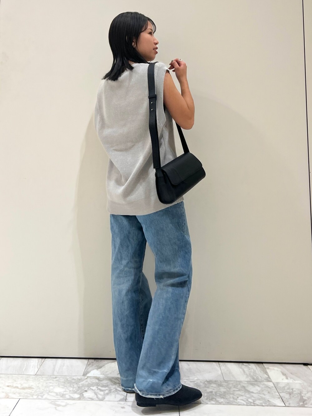 ブルー系のデニムパンツ、ブラック系のショルダーバッグ、シルバー系のベストを着用したレディースの夏コーディネートの3枚目の写真