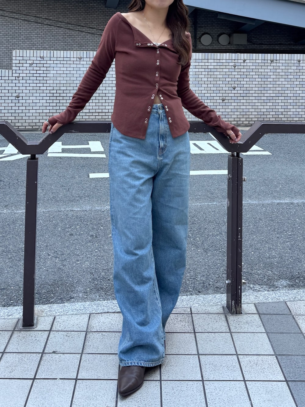 ブルー系のデニムパンツ、ブラウン系のTシャツ/カットソー、ブラウン系のブーツを着用したレディースの秋コーディネートの5枚目の写真