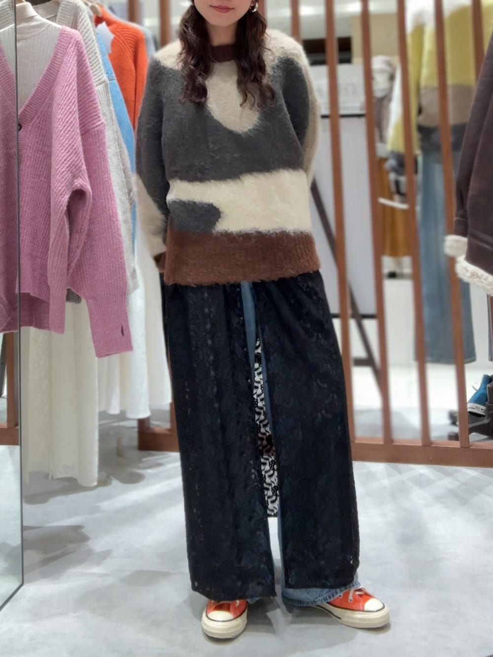 グレー系のニット/セーター、ブラック系のワンピース、ブルー系のデニムパンツを着用したレディースの秋コーディネートの2枚目の写真