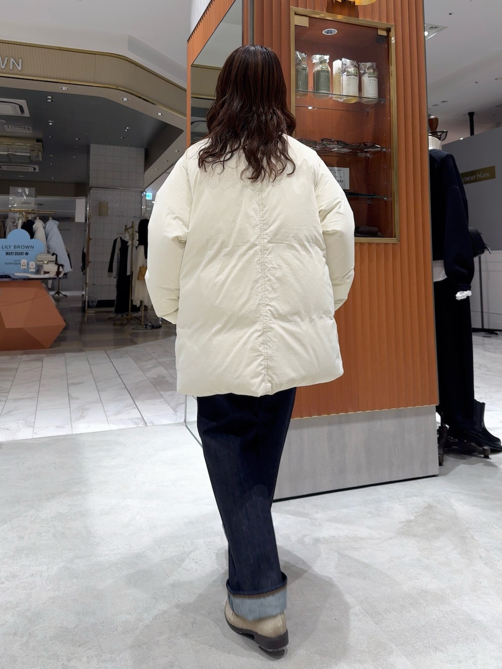 ホワイト系のダウンジャケット/コート、グレー系のニット/セーター、ブルー系のデニムパンツを着用したレディースの冬コーディネートの4枚目の写真