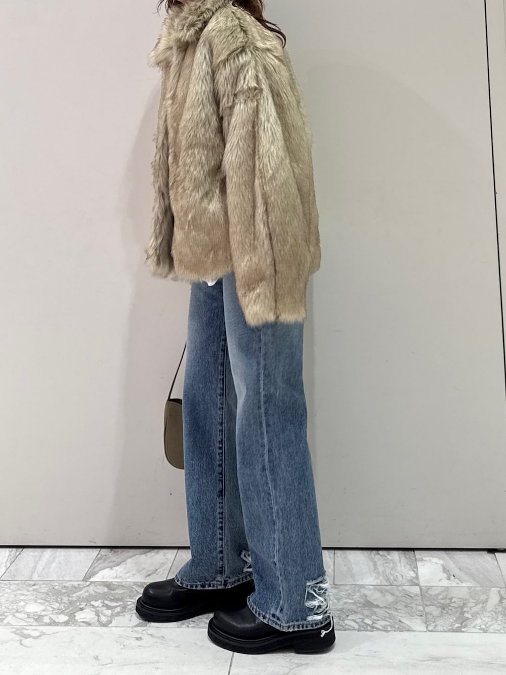 ベージュ系のダウンジャケット/コート、グリーン系のハンドバッグ、ブルー系のデニムパンツを着用したレディースの冬コーディネートの5枚目の写真