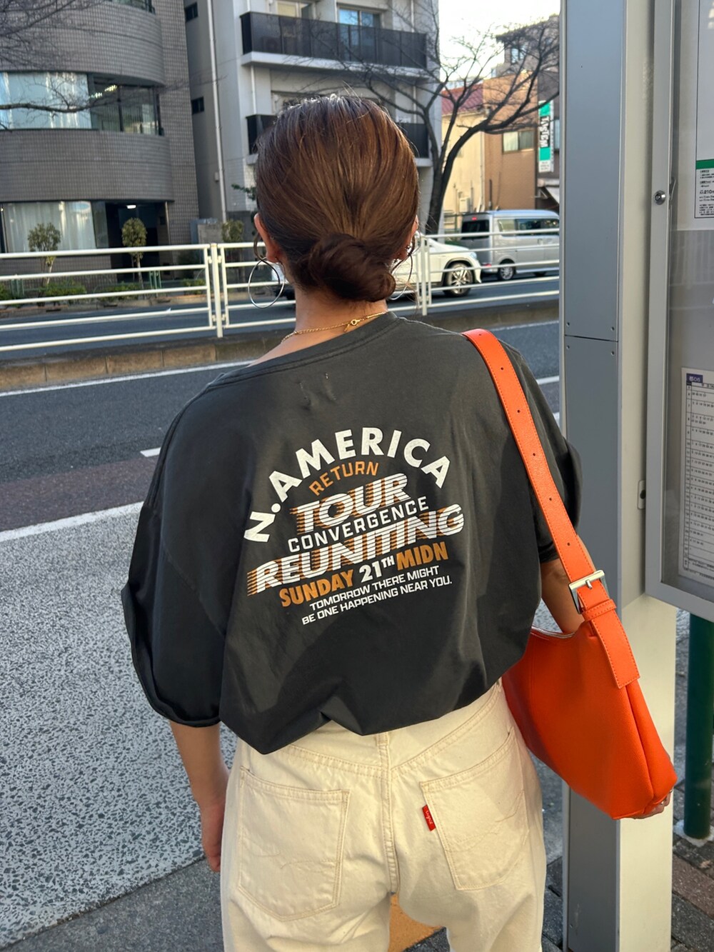 グレー系のTシャツ/カットソー、ホワイト系のデニムパンツ、オレンジ系のショルダーバッグを着用したレディースの春コーディネートの5枚目の写真