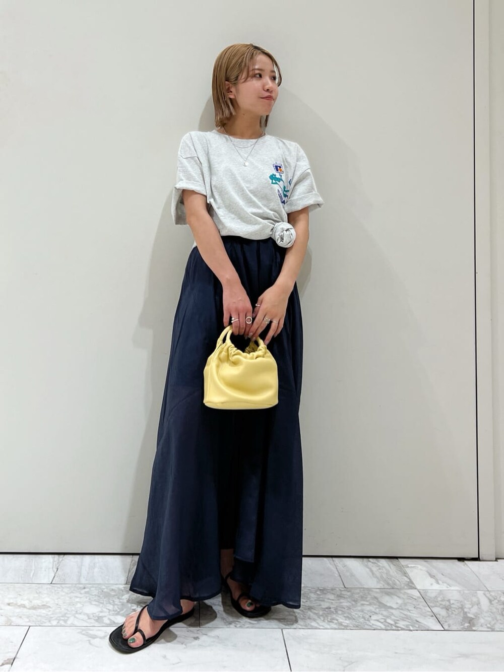ブラック系のサンダル、ブルー系のスカート、イエロー系のハンドバッグを着用したレディースの春コーディネートの2枚目の写真