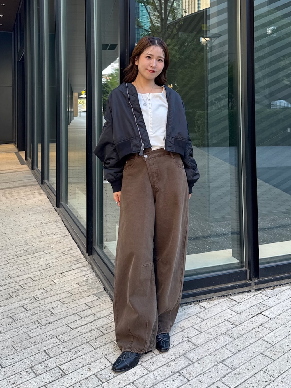 ブラウン系のデニムパンツ、ホワイト系のTシャツ/カットソー、ブラック系のMA-1を着用したレディースの秋コーディネートの6枚目の写真