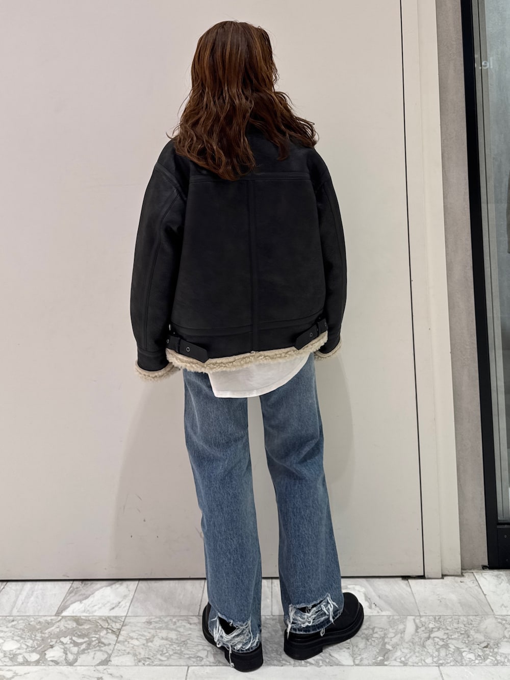 ブラック系のニット/セーター、ホワイト系のTシャツ/カットソー、ブラック系のブーツを着用したレディースの冬コーディネートの6枚目の写真