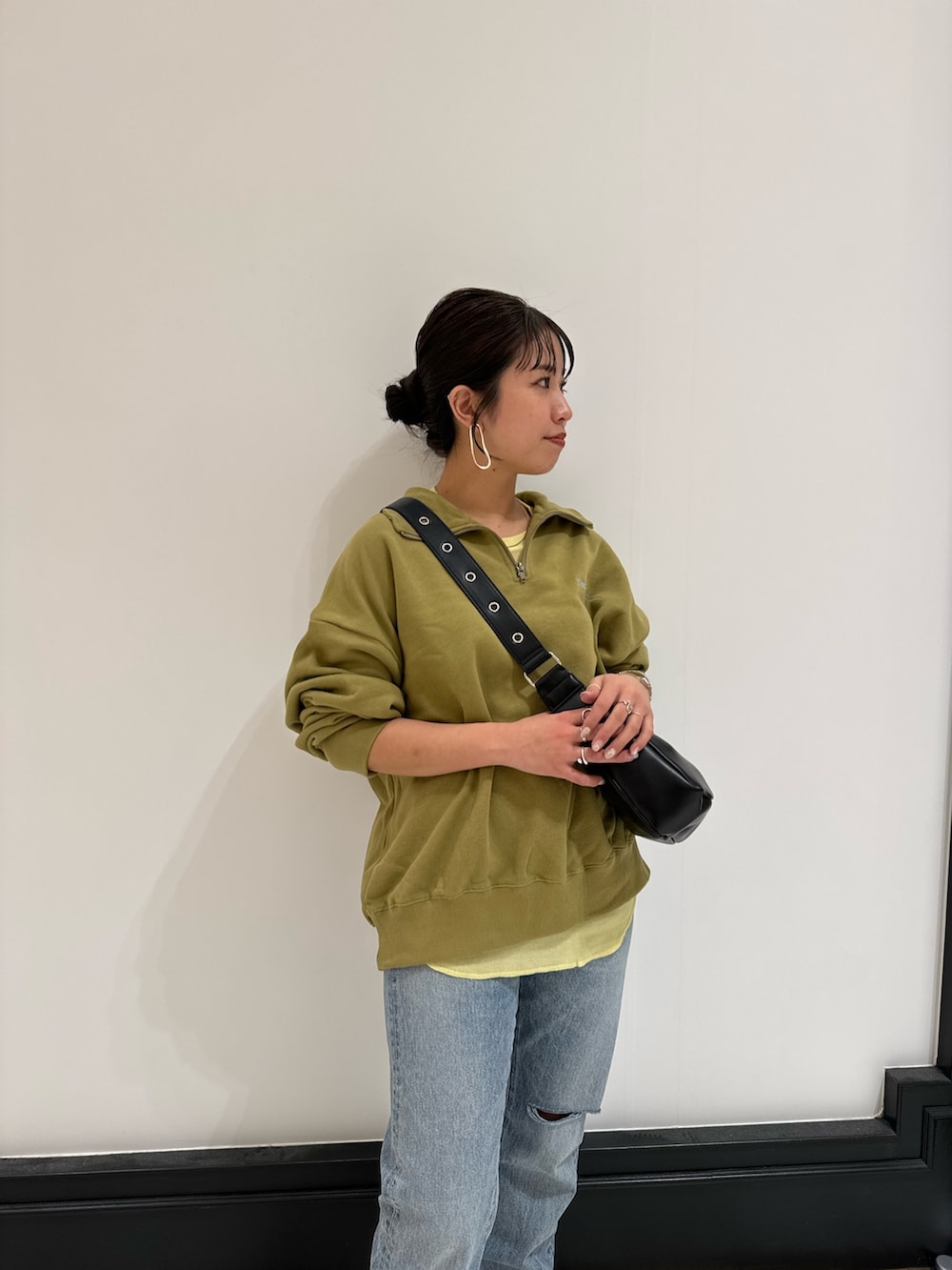 グリーン系のスウェット、ブラック系のショルダーバッグ、イエロー系のTシャツ/カットソーを着用したレディースの冬コーディネートの9枚目の写真