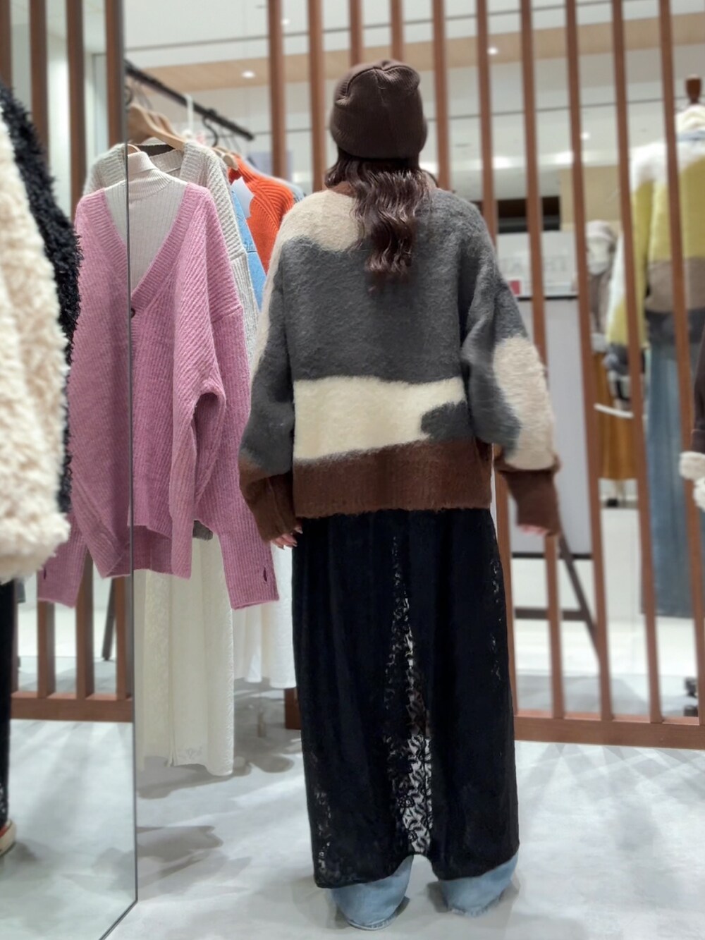 グレー系のニット/セーター、ブラック系のワンピース、ブルー系のデニムパンツを着用したレディースの秋コーディネートの5枚目の写真