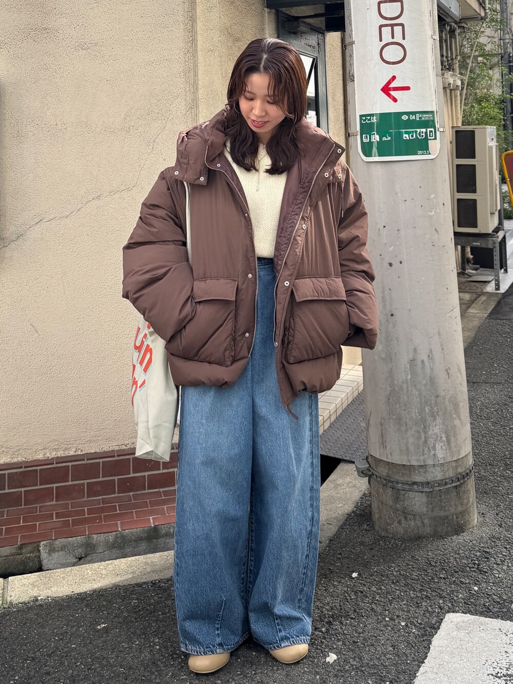 ブラウン系のダウンジャケット/コート、ホワイト系のニット/セーター、ブルー系のデニムパンツを着用したレディースの秋コーディネートの8枚目の写真