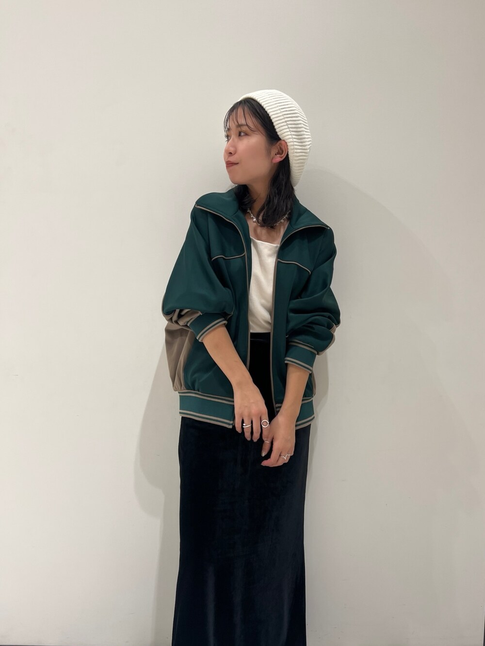 ブラック系のスカート、グリーン系のブルゾン、ホワイト系のキャミソールを着用したレディースの秋コーディネートの9枚目の写真