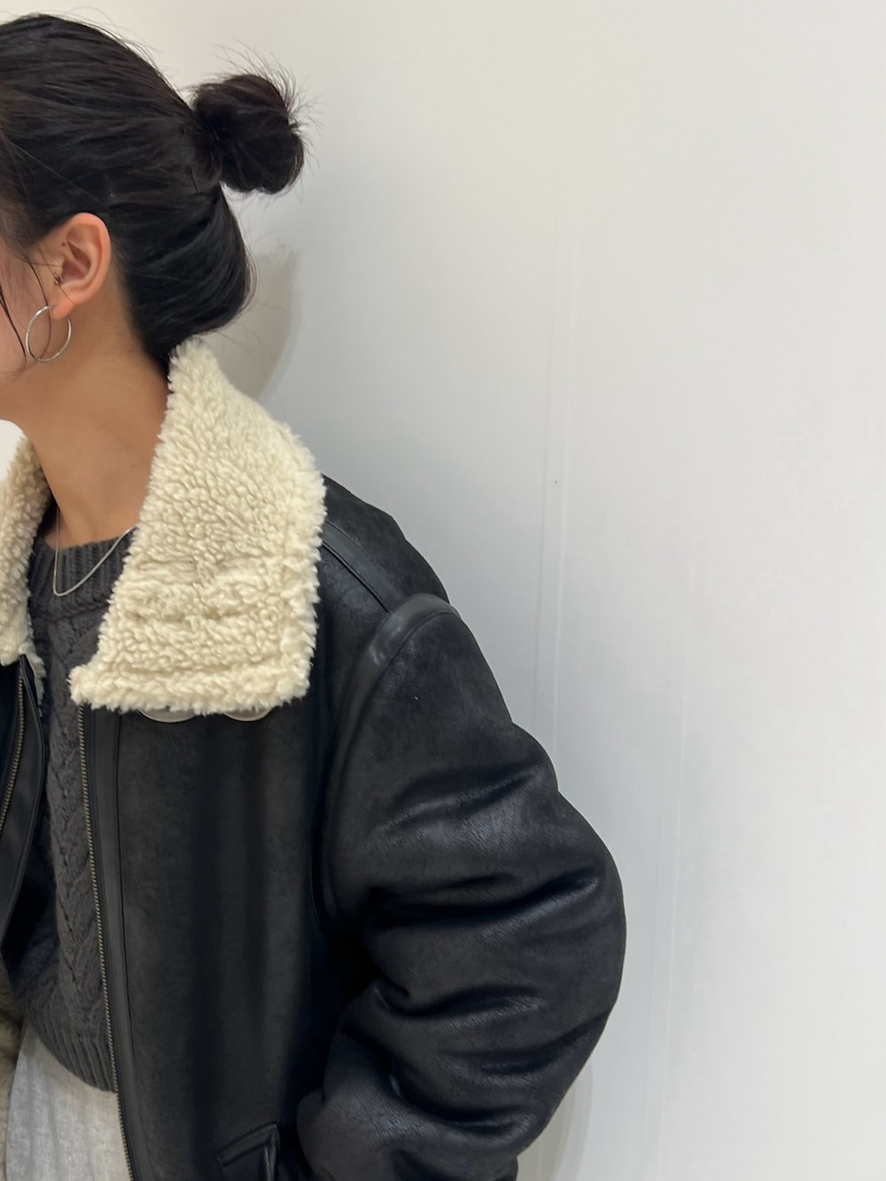 ホワイト系のハンドバッグ、グレー系のニット/セーター、ブラック系のムートンコートを着用したレディースの冬コーディネートの4枚目の写真