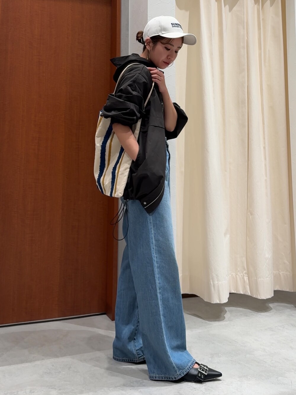 ブラック系のブルゾン、ブラック系のTシャツ/カットソー、ブルー系のデニムパンツを着用したレディースの春コーディネートの7枚目の写真