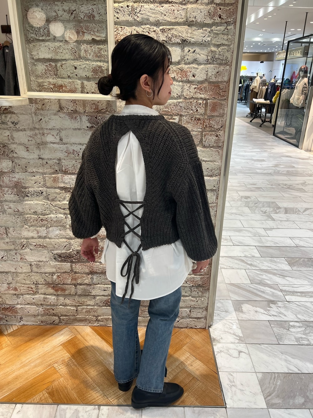 グレー系のニット/セーター、ブルー系のデニムパンツ、ブラック系のローファーを着用したレディースの秋コーディネートの5枚目の写真