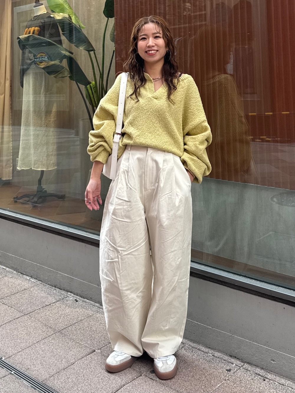 ホワイト系のチノパンツ、グリーン系のニット/セーター、ホワイト系のショルダーバッグを着用したレディースの冬コーディネートの5枚目の写真