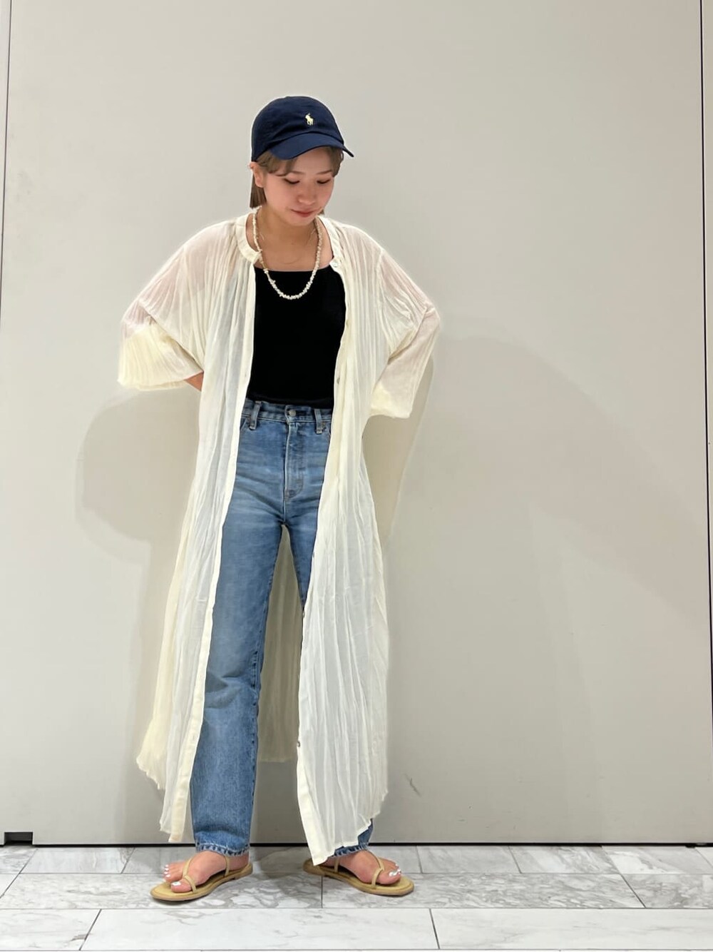 ブルー系のデニムパンツ、グリーン系のサンダル、ブラック系のキャミソールを着用したレディースの夏コーディネートの2枚目の写真