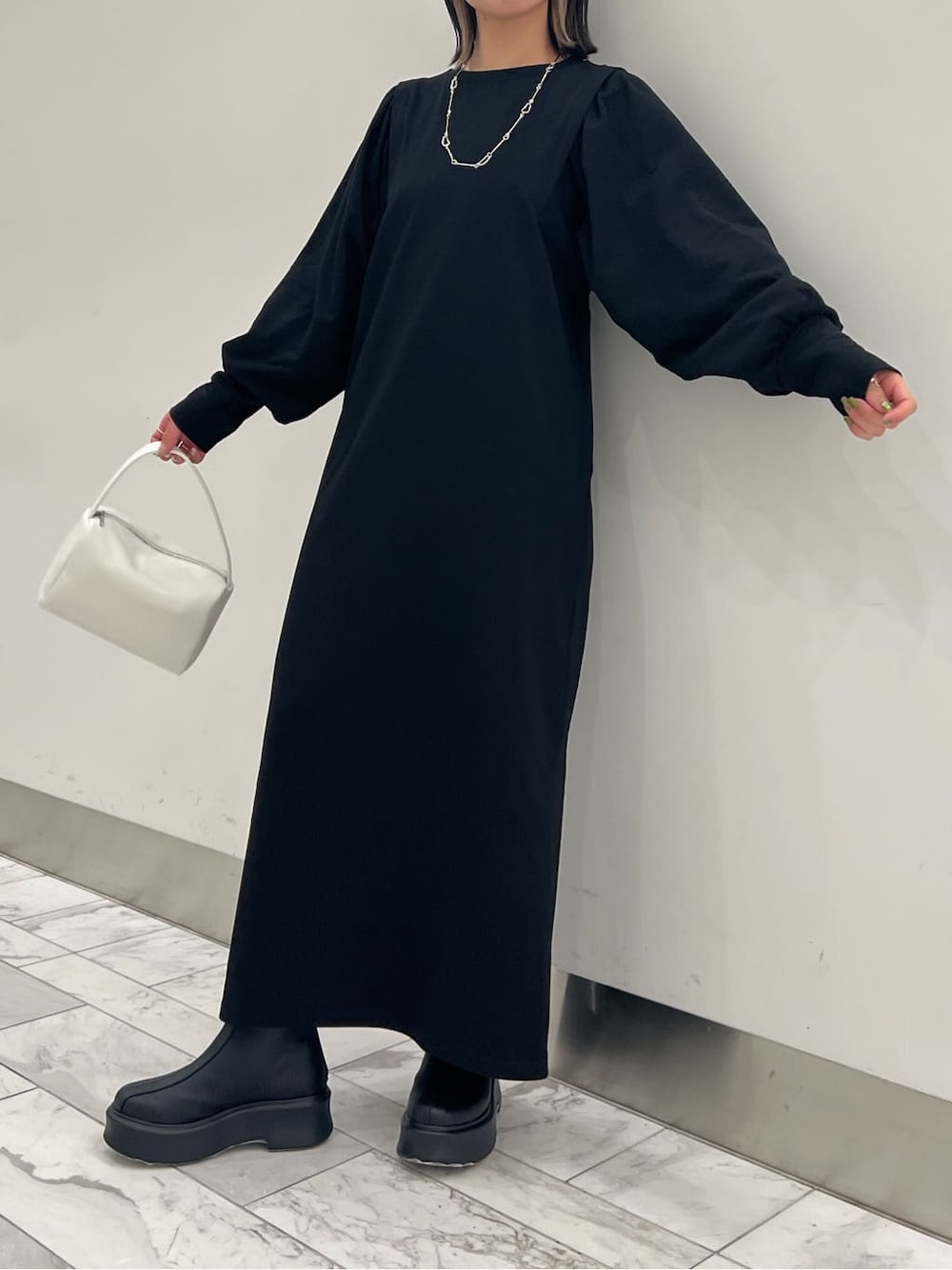 ブラック系のワンピース、ブラック系のブーツ、ホワイト系のハンドバッグを着用したレディースの冬コーディネートの3枚目の写真