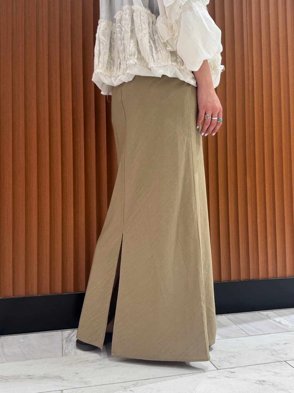 ベージュ系のスカート、ホワイト系のシャツ/ブラウス、ブラック系のキャミソールを着用したレディースの春コーディネートの10枚目の写真