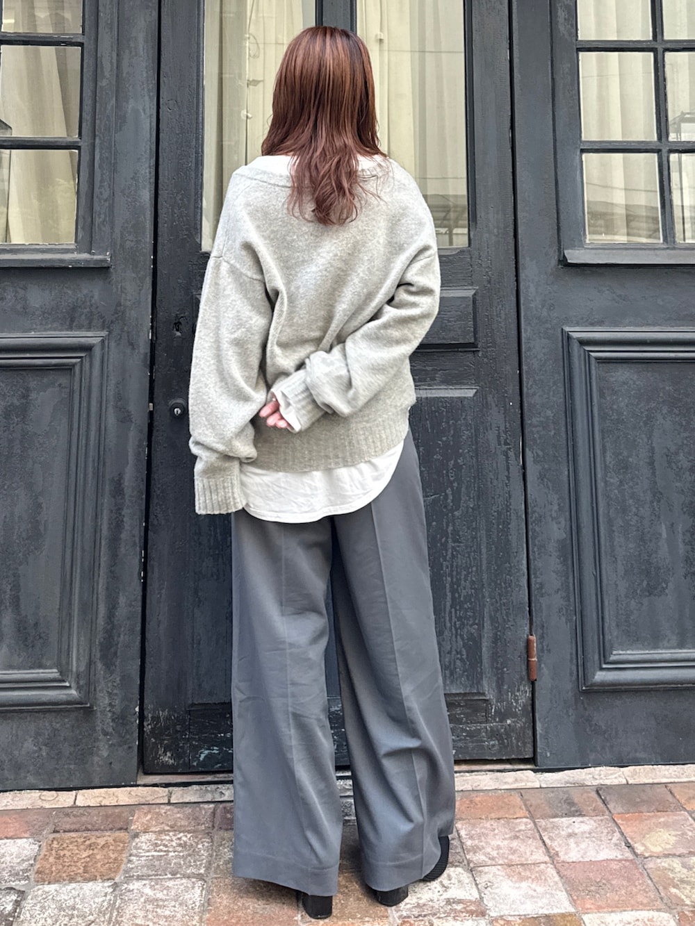 グレー系のニット/セーター、ホワイト系のTシャツ/カットソー、グレー系のその他パンツを着用したレディースの冬コーディネートの3枚目の写真