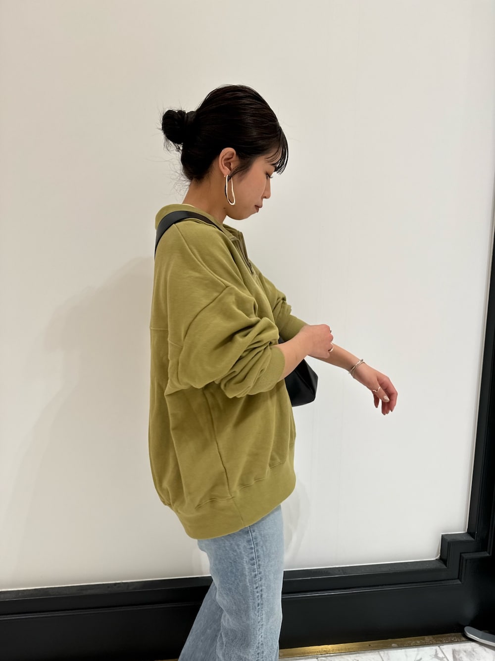 グリーン系のスウェット、ブラック系のショルダーバッグ、イエロー系のTシャツ/カットソーを着用したレディースの冬コーディネートの5枚目の写真