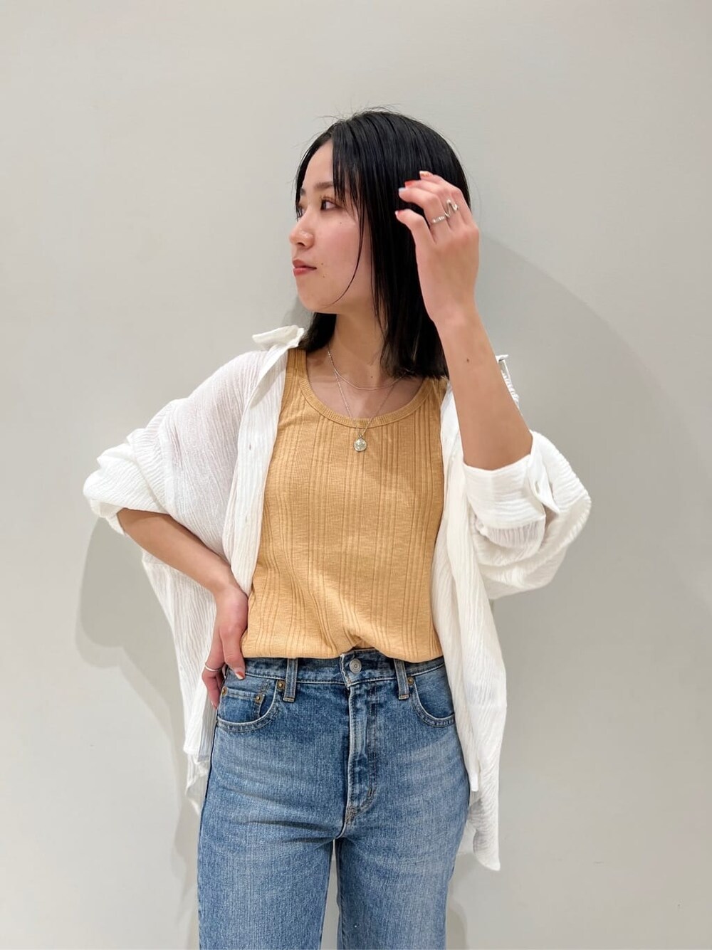 ブルー系のデニムパンツ、オレンジ系のタンクトップ、ホワイト系のシャツ/ブラウスを着用したレディースの春コーディネートの6枚目の写真