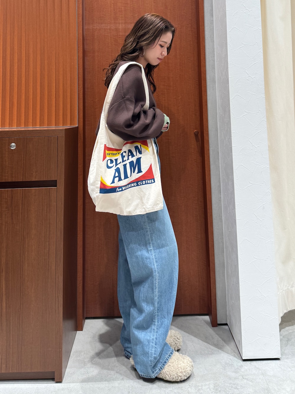 ブルー系のデニムパンツ、ブラウン系のニット/セーター、ホワイト系のトートバッグを着用したレディースの冬コーディネートの3枚目の写真