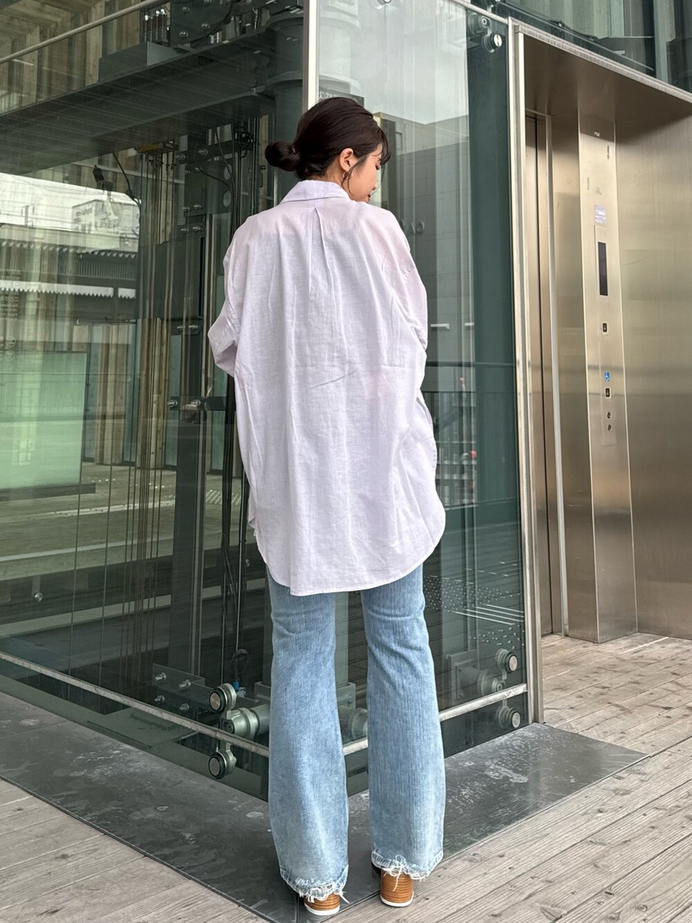 グレー系のTシャツ/カットソー、ブルー系のデニムパンツ、ブラック系のサンダルを着用したレディースの春コーディネートの6枚目の写真