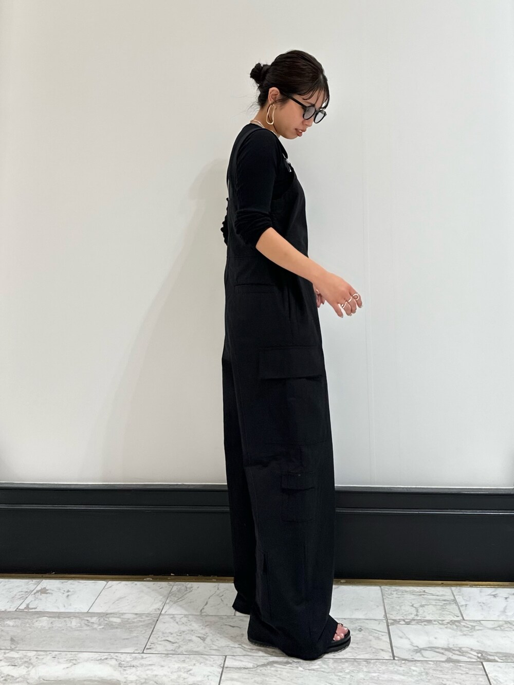 ブラック系のつなぎ/オールインワン、ブラック系のTシャツ/カットソー、ブラック系のサンダルを着用したレディースの冬コーディネートの2枚目の写真