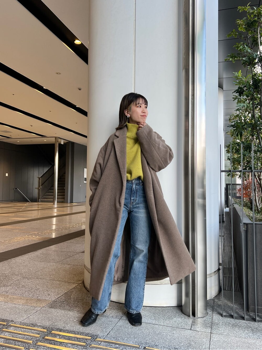 ベージュ系のチェスターコート、ブルー系のデニムパンツ、グリーン系のニット/セーターを着用したレディースの冬コーディネートの3枚目の写真