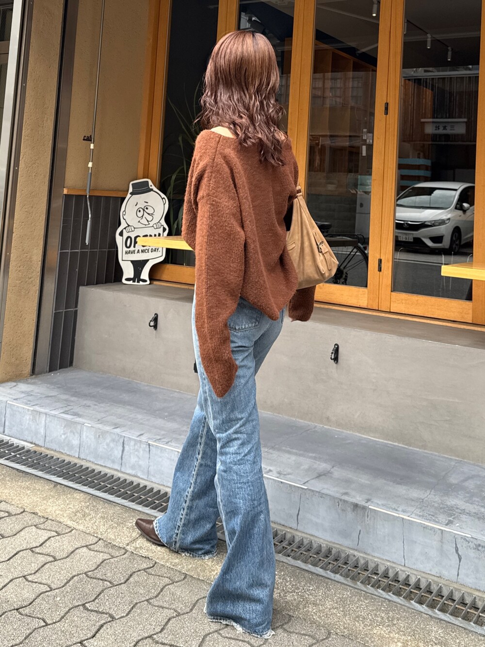 ブルー系のデニムパンツ、ブラウン系のブーツ、ブラウン系のニット/セーターを着用したレディースの秋コーディネートの5枚目の写真