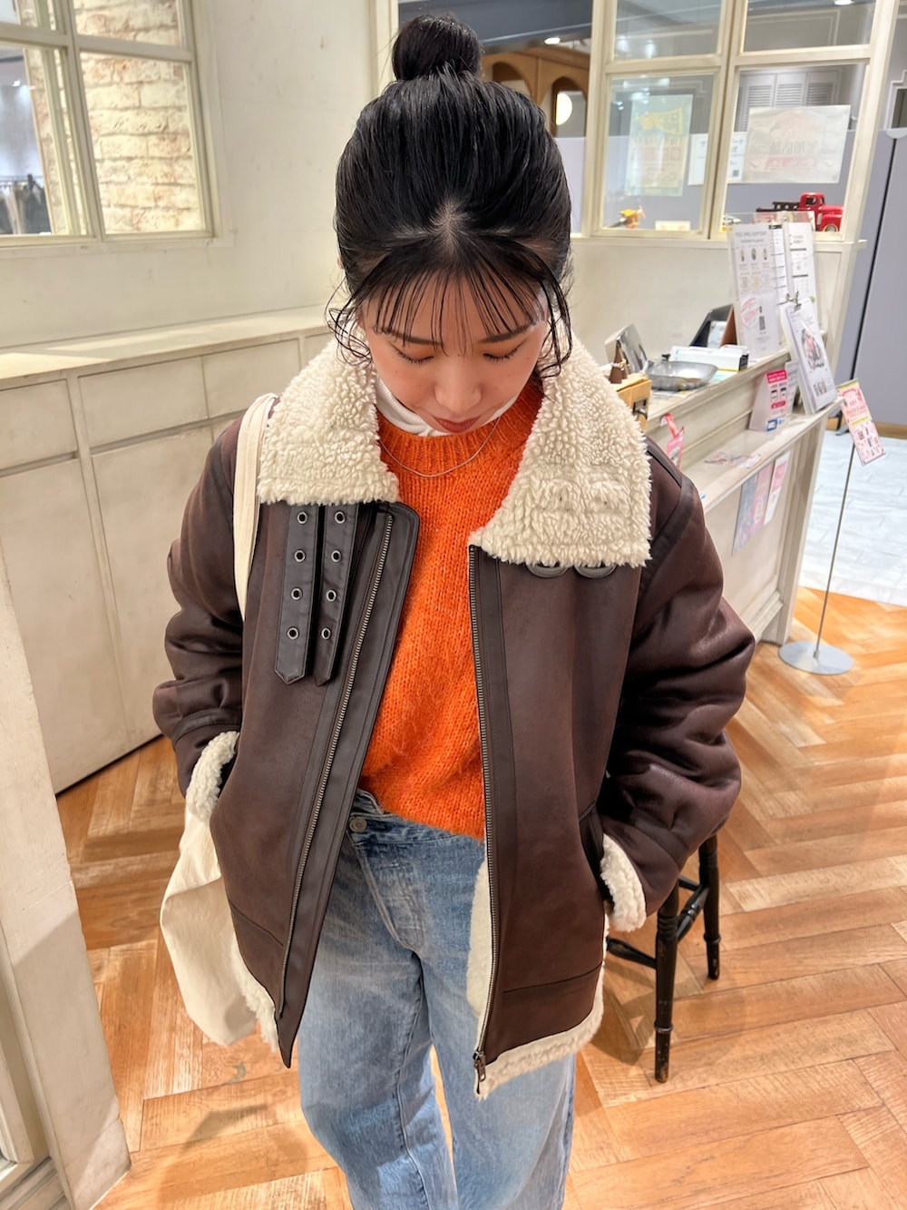 オレンジ系のニット/セーター、ホワイト系のTシャツ/カットソー、ブルー系のデニムパンツを着用したレディースの冬コーディネートの4枚目の写真