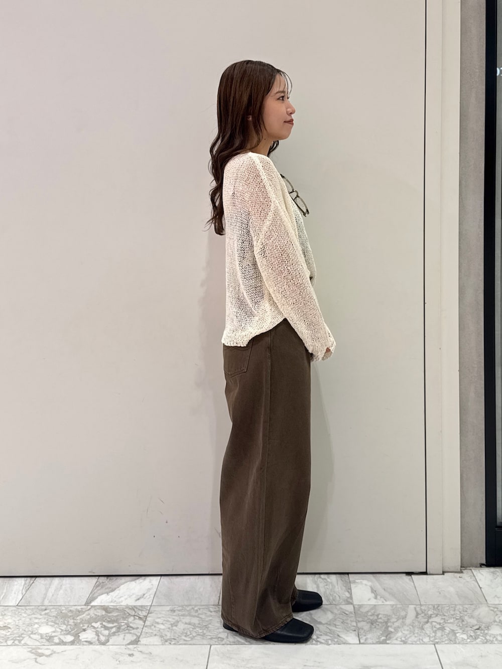 ブラウン系のデニムパンツ、ホワイト系のニット/セーター、ブラック系のサンダルを着用したレディースの秋コーディネートの4枚目の写真