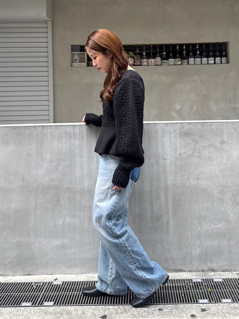 ブラック系のニット/セーター、ブルー系のデニムパンツ、ブラック系のサンダルを着用したレディースの秋コーディネートの4枚目の写真