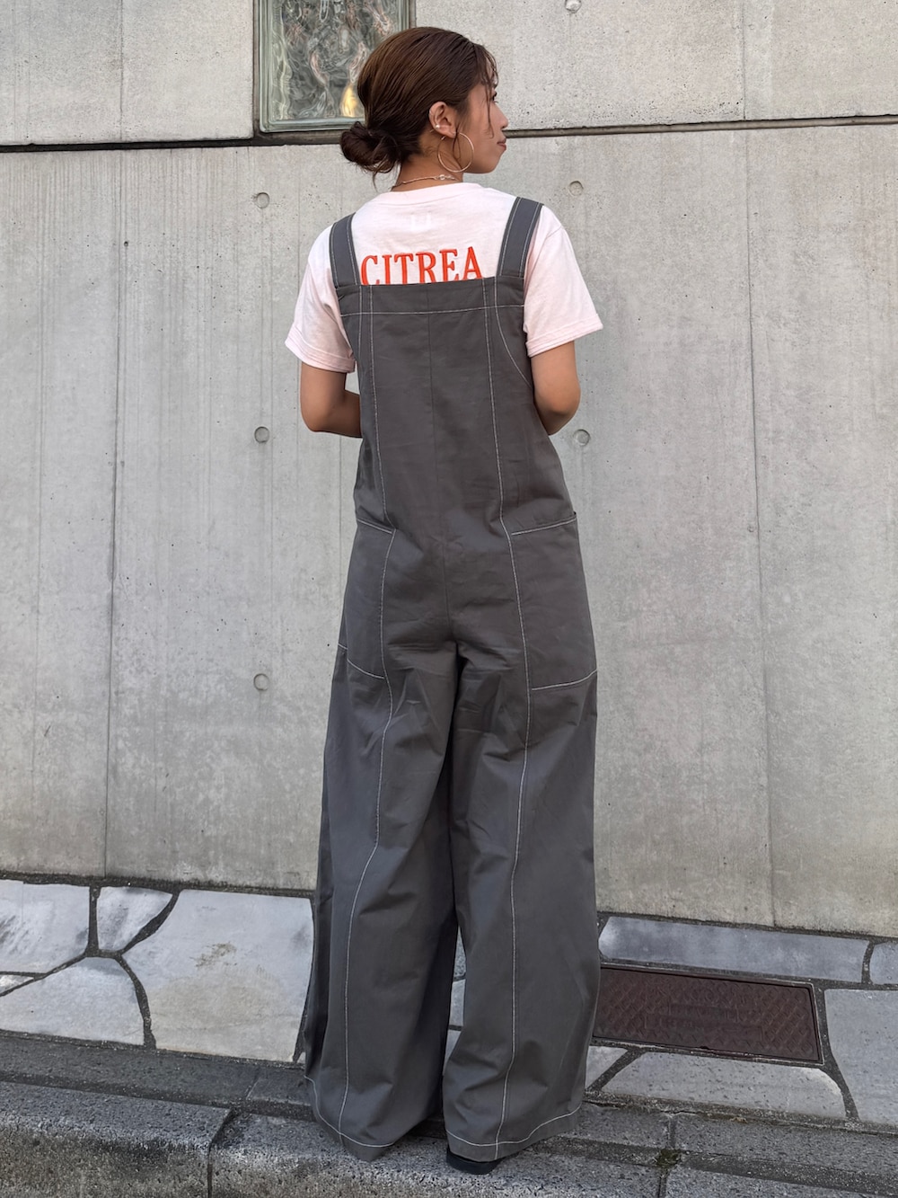 ピンク系のTシャツ/カットソー、ブラック系のサロペット/オーバーオール、ブラック系のサンダルを着用したレディースの春コーディネートの7枚目の写真