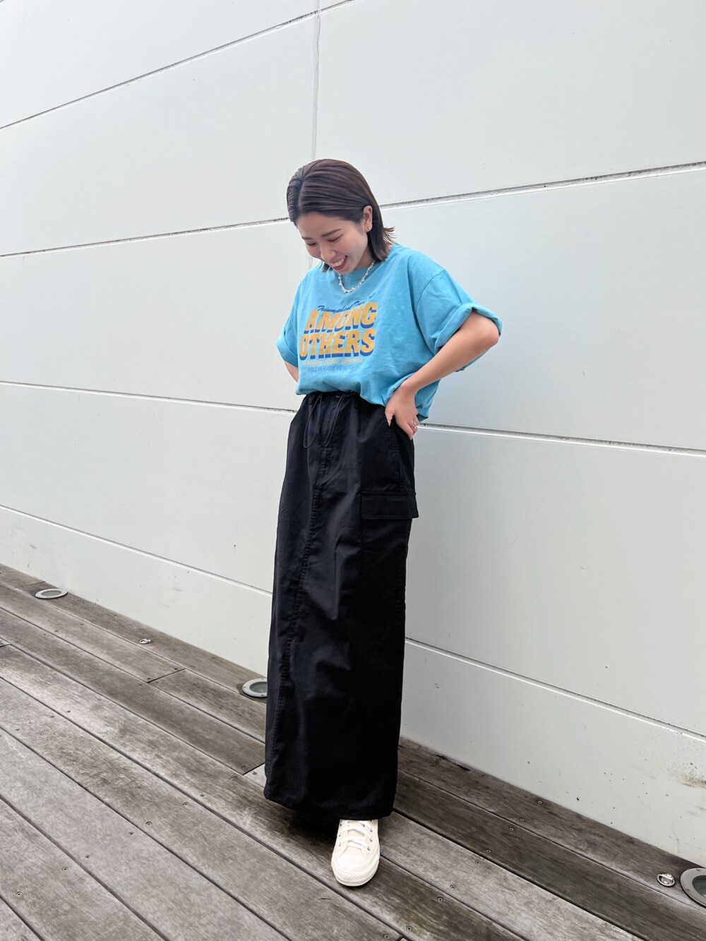 ブルー系のTシャツ/カットソー、ブラック系のスカート、ホワイト系のスニーカーを着用したレディースの春コーディネートの7枚目の写真