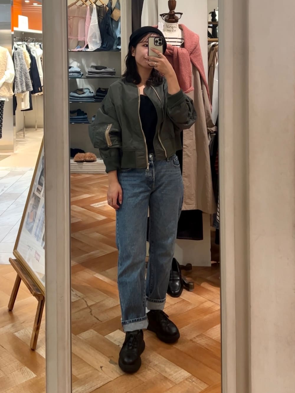 ブラック系のキャミソール、ブルー系のデニムパンツ、グリーン系のブルゾンを着用したレディースの秋コーディネートの3枚目の写真