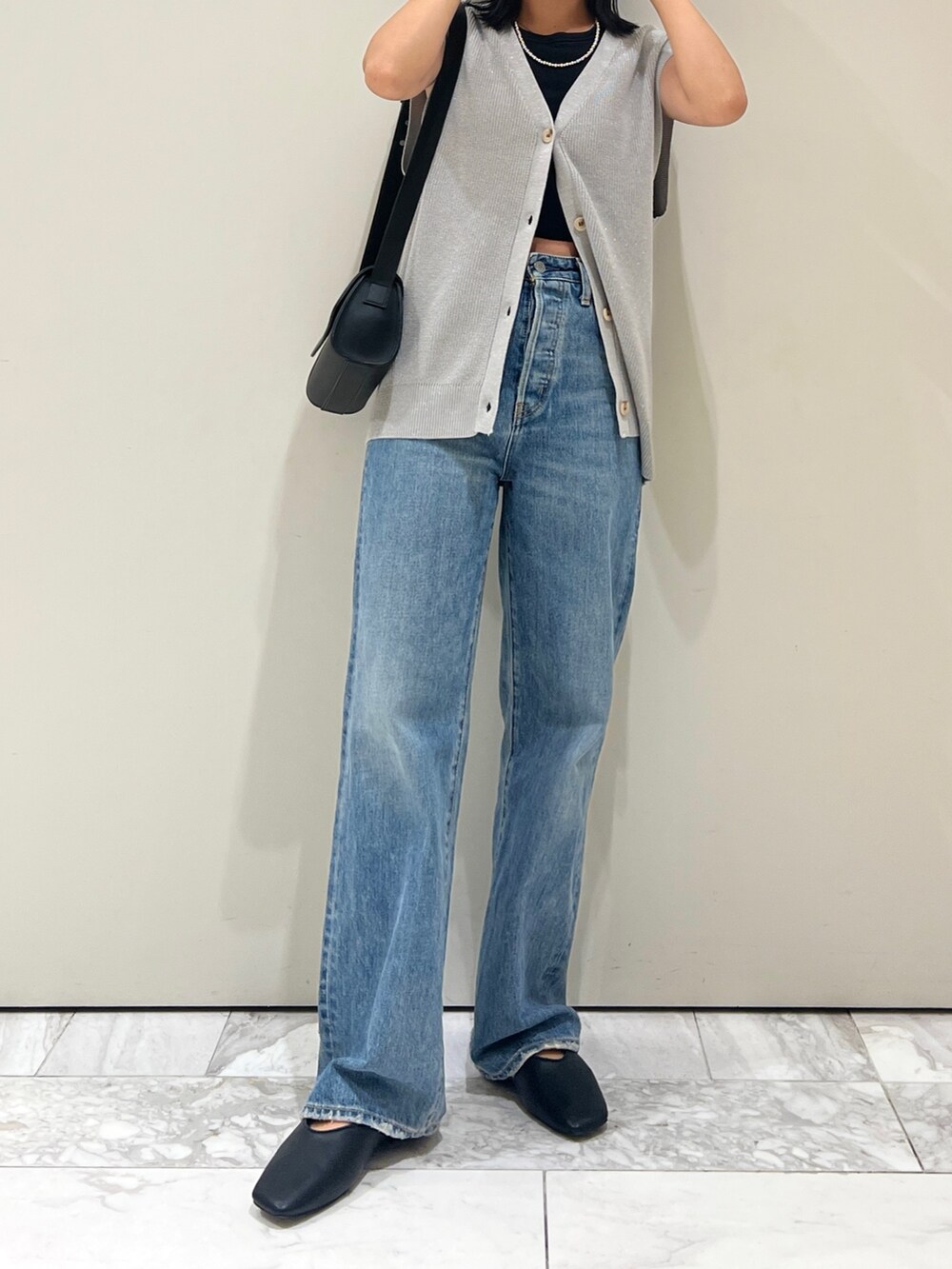 ブルー系のデニムパンツ、ブラック系のショルダーバッグ、シルバー系のベストを着用したレディースの夏コーディネートの2枚目の写真