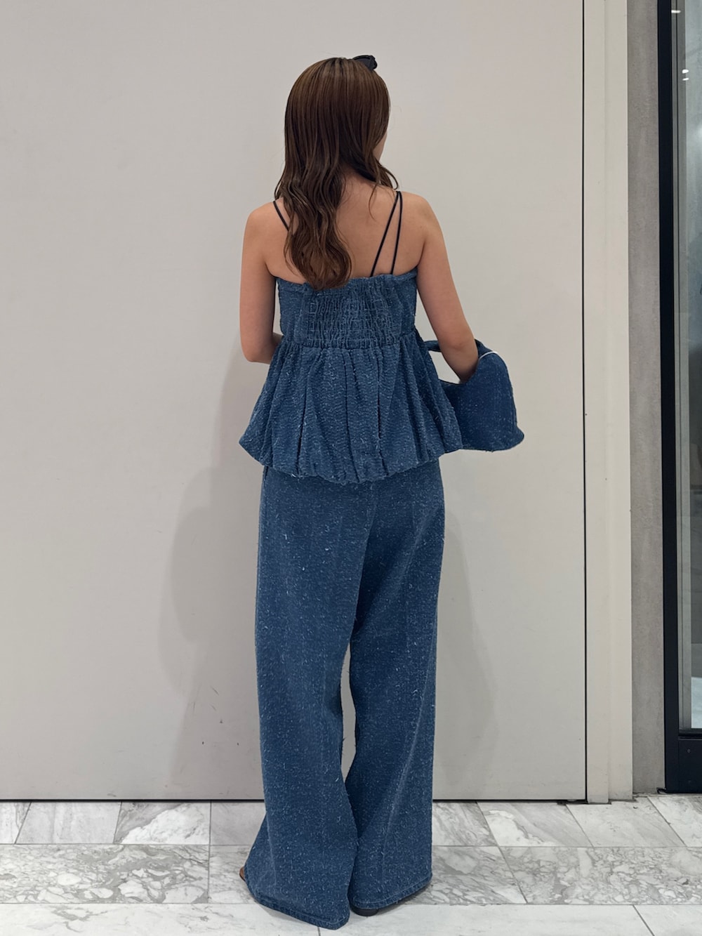 ブルー系のチューブトップ、ブルー系のデニムパンツ、ブルー系のハンドバッグを着用したレディースの春コーディネートの3枚目の写真