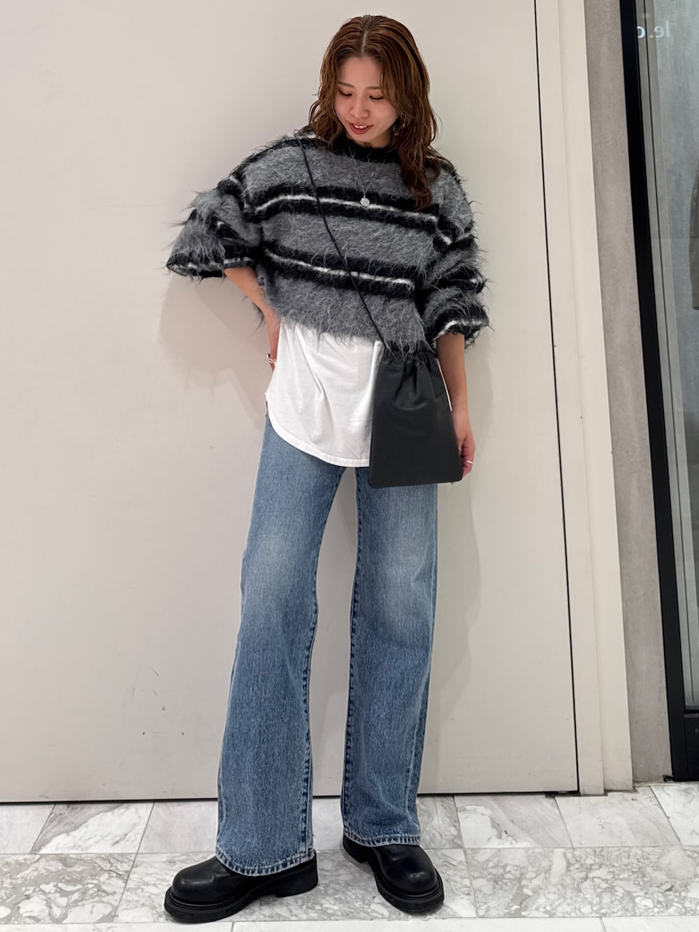 ブラック系のニット/セーター、ホワイト系のTシャツ/カットソー、ブルー系のデニムパンツを着用したレディースの冬コーディネートの2枚目の写真