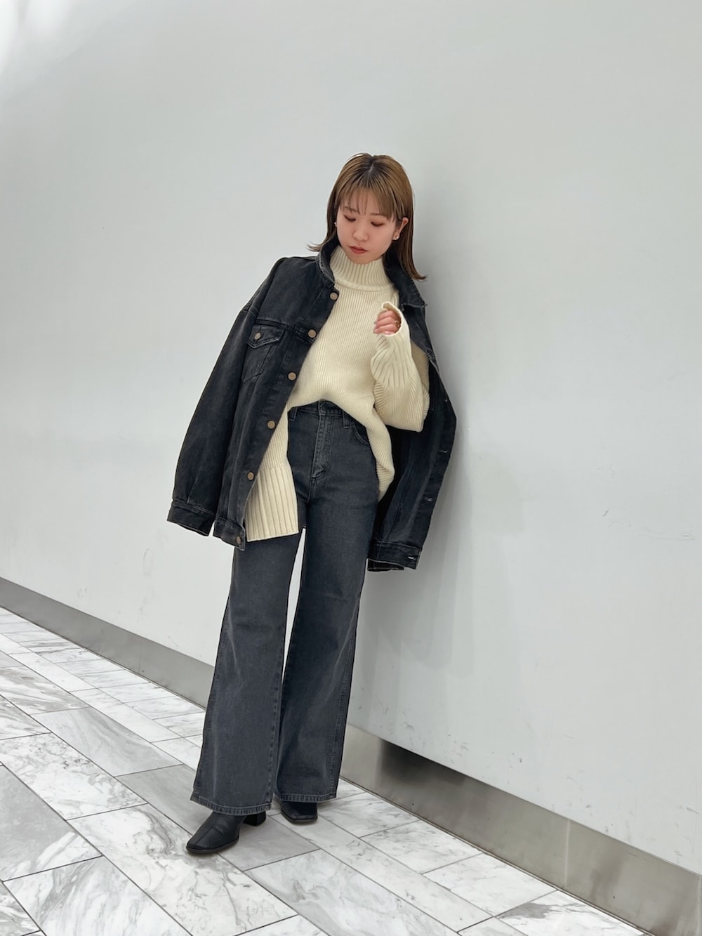 ブラック系のデニムジャケット、ホワイト系のニット/セーター、ブラック系のデニムパンツを着用したレディースの秋コーディネートの3枚目の写真