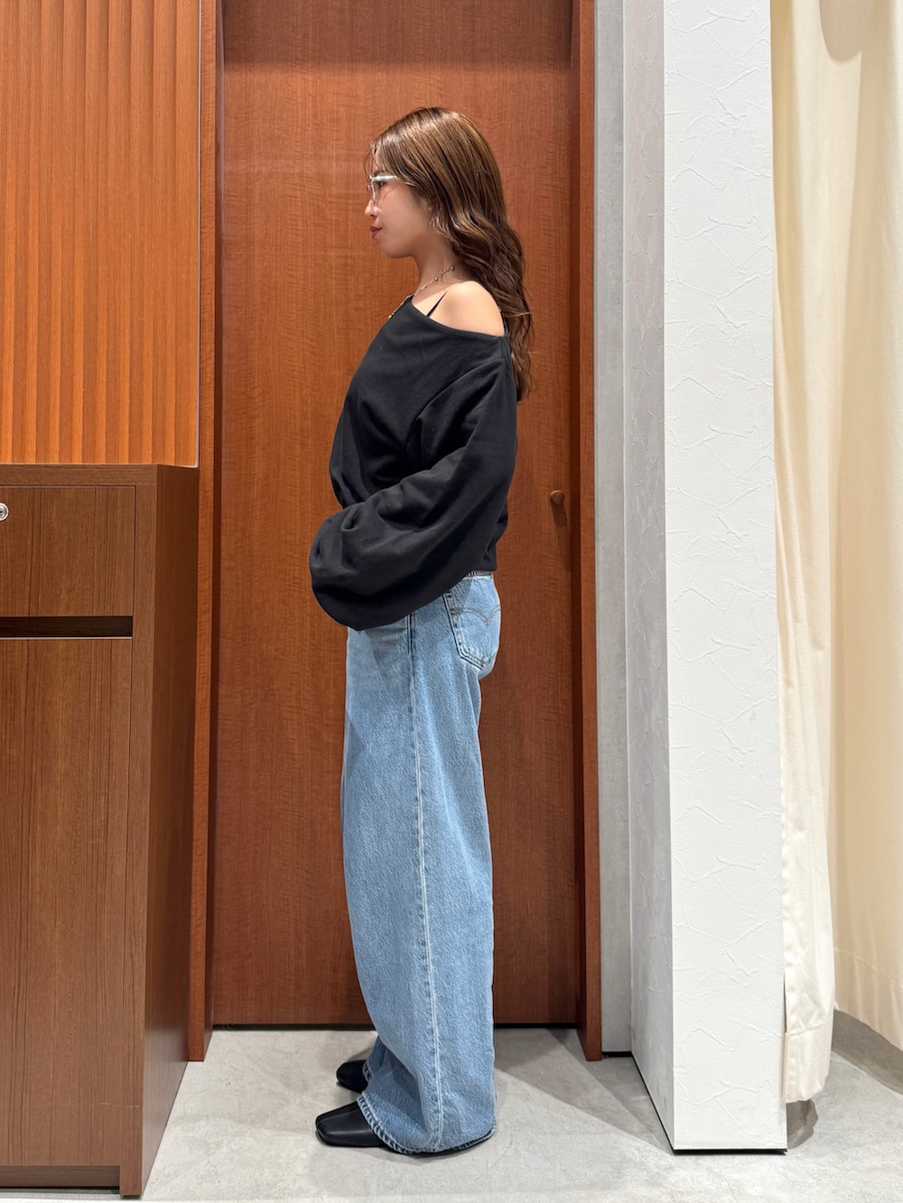 ブルー系のデニムパンツ、ブラック系のスウェット、シルバー系のメガネを着用したレディースの秋コーディネートの4枚目の写真