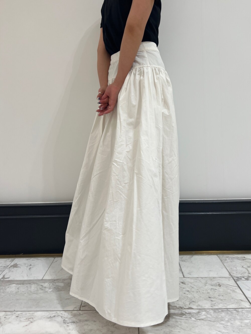 ホワイト系のスカート、ブラック系のTシャツ/カットソー、ブラック系のパンプスを着用したレディースの春コーディネートの7枚目の写真