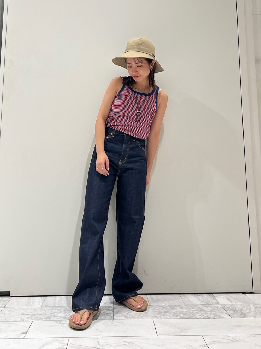 ブルー系のデニムパンツ、ブルー系のタンクトップ、ホワイト系のキャミソールを着用したレディースの夏コーディネートの6枚目の写真