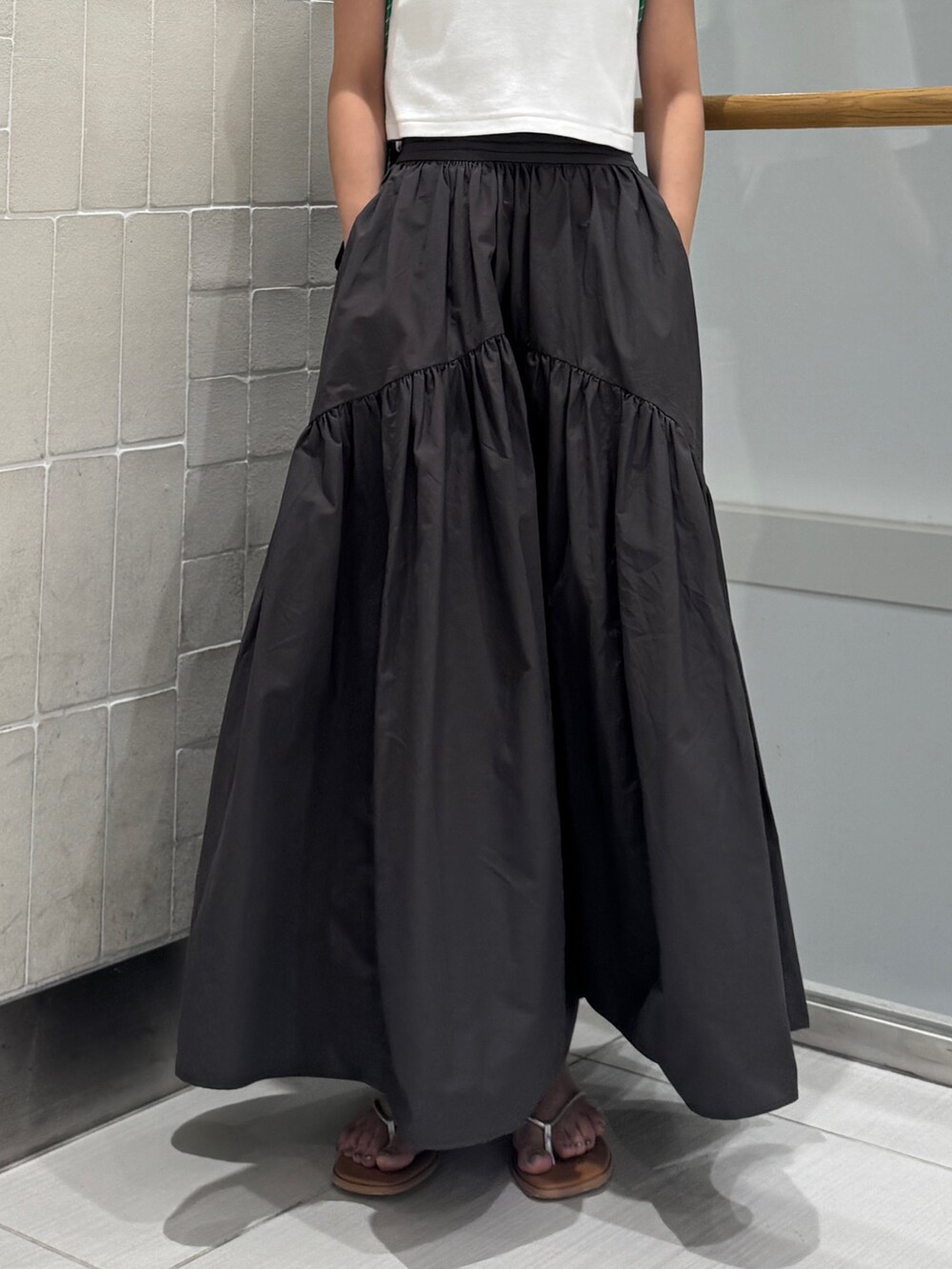 グレー系のスカート、シルバー系のサンダル、ホワイト系のTシャツ/カットソーを着用したレディースの春コーディネートの9枚目の写真