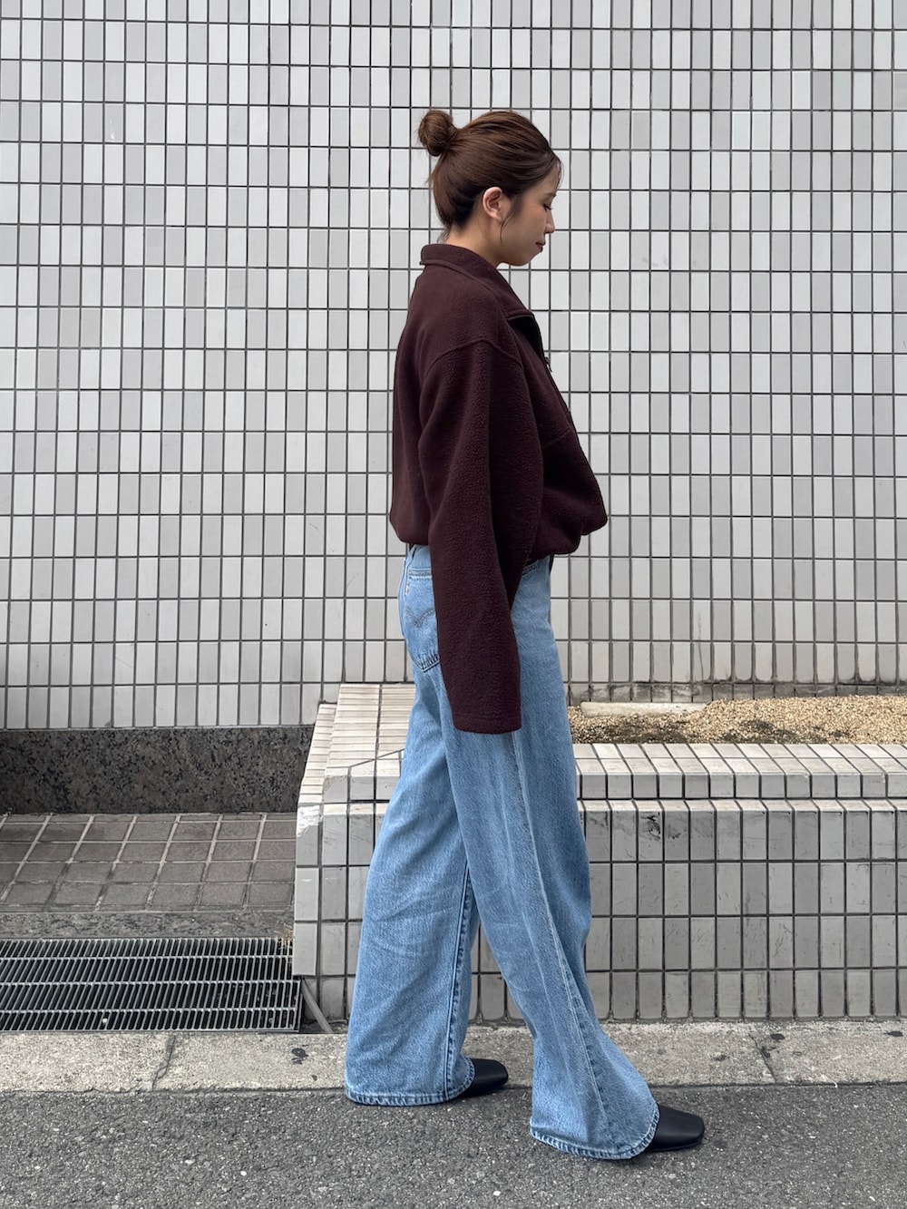 ブラウン系のパーカー、ブルー系のデニムパンツ、ブラック系のサンダルを着用したレディースの秋コーディネートの2枚目の写真