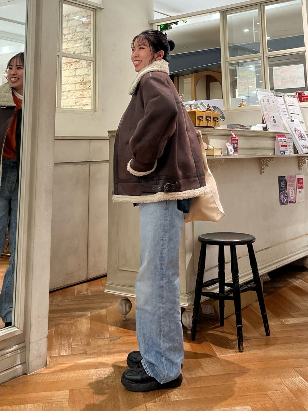 オレンジ系のニット/セーター、ホワイト系のTシャツ/カットソー、ブルー系のデニムパンツを着用したレディースの冬コーディネートの6枚目の写真