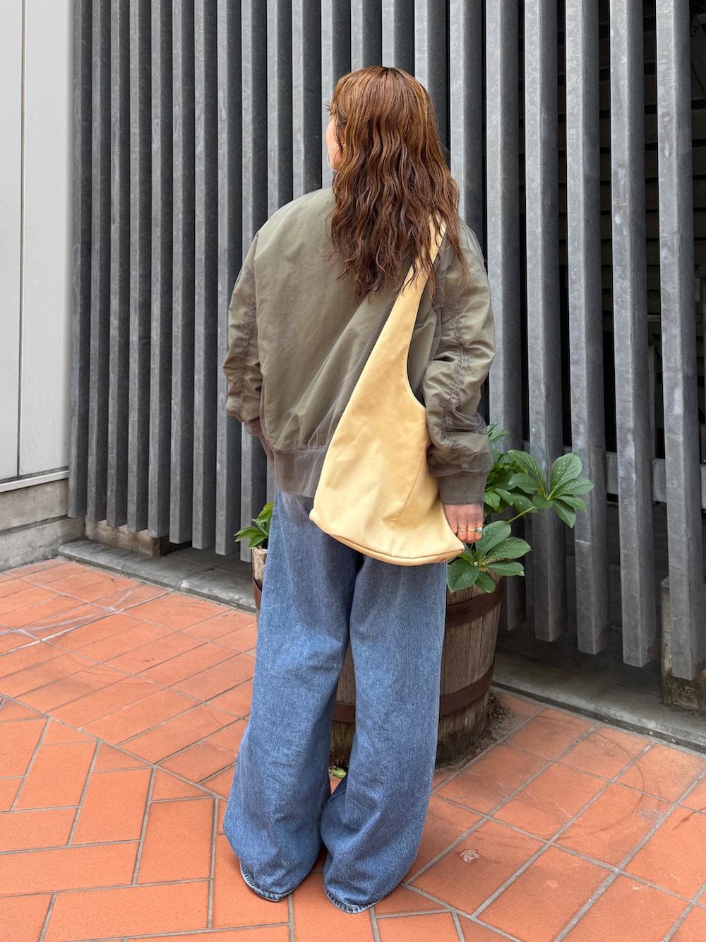 ベージュ系のトートバッグ、ホワイト系のタンクトップ、ブルー系のデニムパンツを着用したレディースの夏コーディネートの4枚目の写真