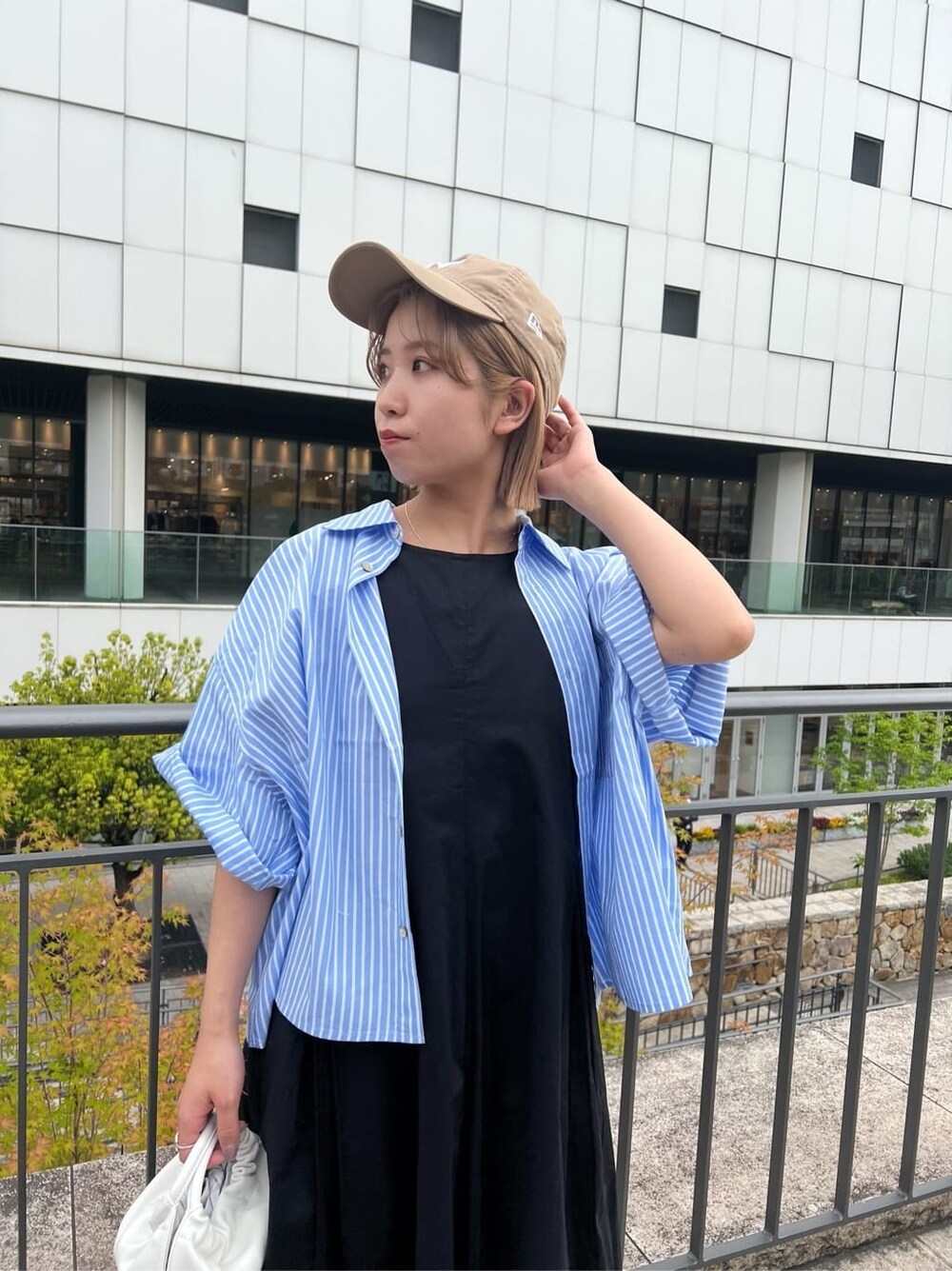 ブラック系のワンピース、ブルー系のシャツ/ブラウス、ホワイト系のハンドバッグを着用したレディースの春コーディネートの6枚目の写真