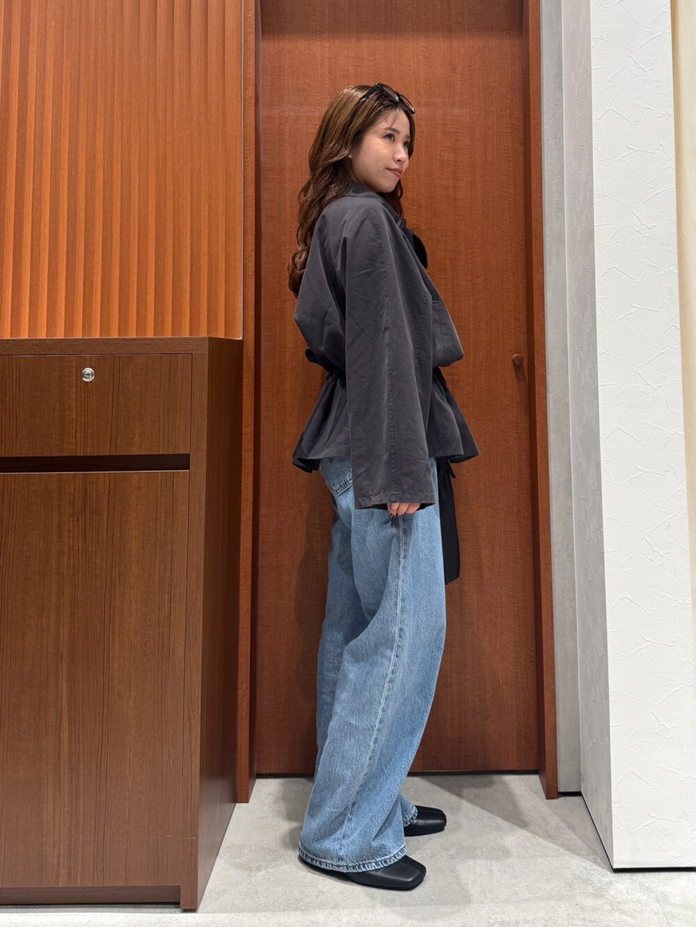 グレー系のトレンチコート、ブルー系のデニムパンツ、シルバー系のネックレスを着用したレディースの秋コーディネートの3枚目の写真