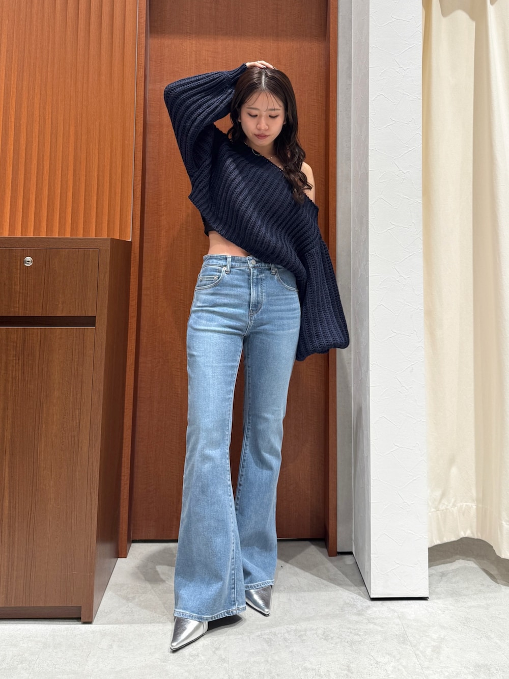 ブルー系のニット/セーター、ブルー系のデニムパンツ、シルバー系のパンプスを着用したレディースの秋コーディネートの7枚目の写真